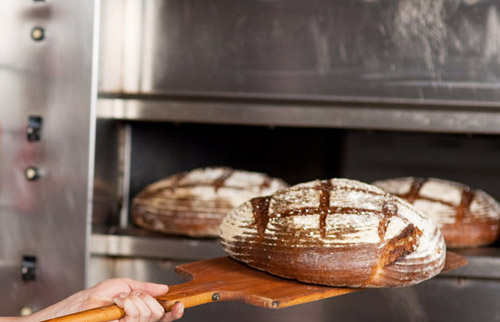 Ein Laib Brot wird aus dem Ofen geholt